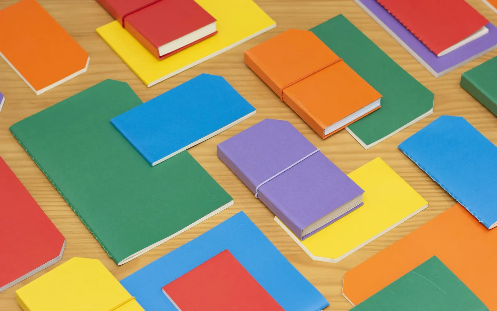 Colourful notebooks laid out on a wooden desk