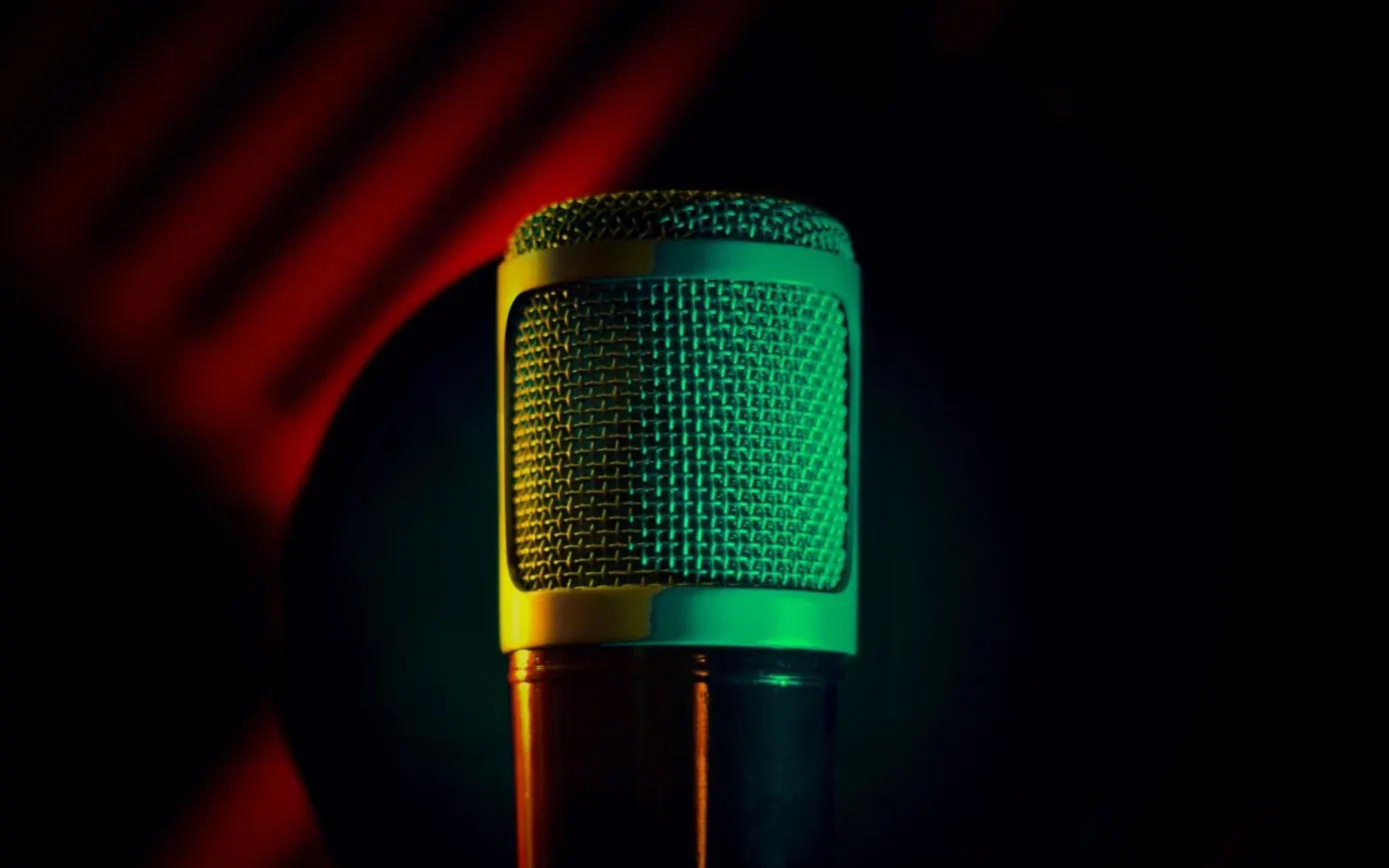 Studio microphone lit green and gold against a red glow