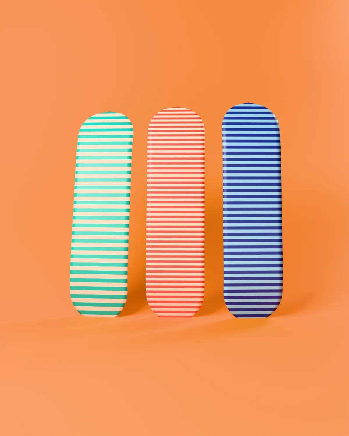 Three Kickflip decks with different graphics leaning on an orange wall